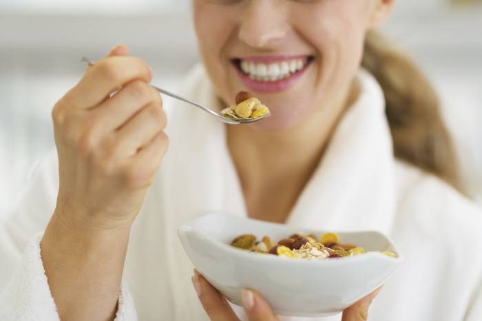 closeup on happy woman in bathrobe having healthy breakfast