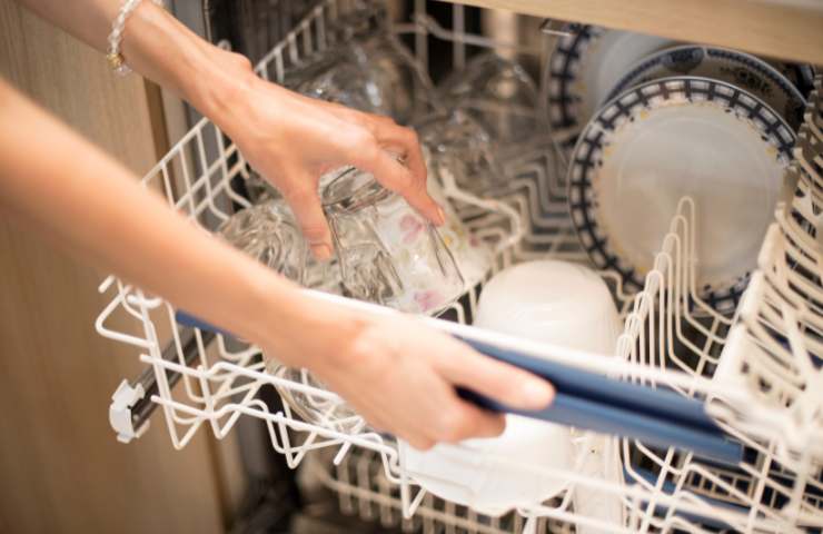 Una donna estrae piatti e bicchieri dalla lavastoviglie