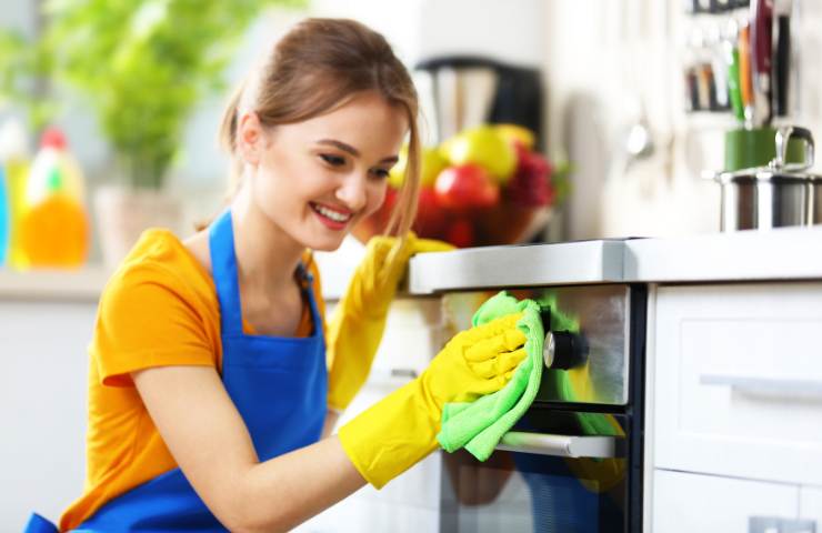 Una donna mentre pulisce il forno