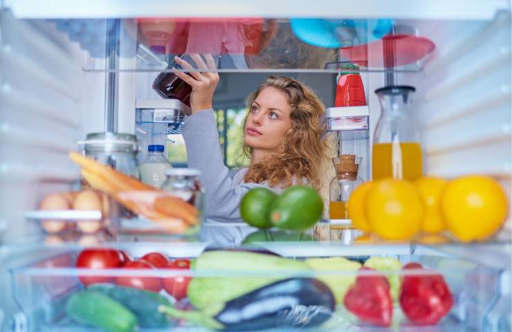 Una donna ripone degli alimenti in frigo