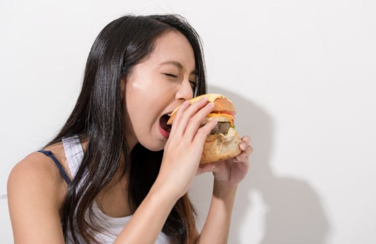 Una ragazza addenta un panino con hamburger
