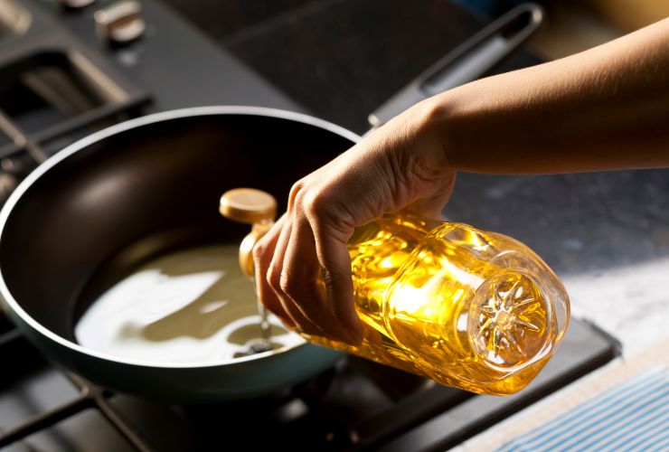 donna che mette olio in padella